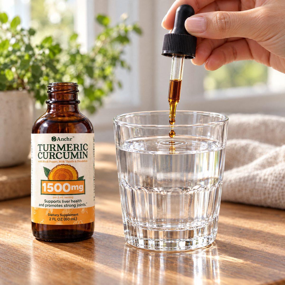 A drop of Anchr Turmeric Curcumin falling from the dropper into a glass of water, next to the open bottle